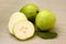 Ripe pearl guava fruits with sliced cross section on a natural wood background