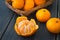 Ripe peeled tangerine and a wicker basket of juicy orange clementines