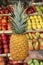 Ripe pineapple in the hand of the seller of the greek vegetable shop on the fruit shelves background