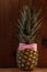 Ripe pineapple with ribbon bow on wooden background. Healthy food, tropical fruits, slimming vegan foods, weight loss