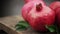 Ripe pomegranate fruit with pomegranate leaves rotate on wooden board.