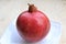 Ripe pomegranate on a glossy plate.