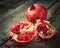 Ripe pomegranate slice and whole red garnet fruit on table.