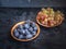 Ripe prunes and grapes in a bamboo cup closeup on a dark wooden background.