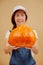 Ripe pumpkin for the Halloween holiday is held by a blurred farmer woman.