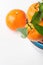 Ripe raw bright orange tangerines with stem green leaves on branch fin stacked blue and white ceramic bowls on wood kitchen table