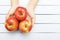 Ripe red apples from rural garden on teenage hands. Wooden background for copy space. Top view