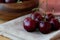 Ripe red cherries in a wooden plate with a glass of juice a brown towel on a wooden background.