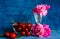 Ripe red cherry in a glass bowl with pink peonies