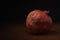 Ripe red dried pomegranate on a wooden table on a black background. minimalistic moody still life with copy space