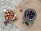 Ripe red gooseberries and leaves lie in a white metal mug on the background of burlap. Cherries in a glass jar next