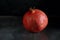 Ripe red pomegranate lies on a dark concrete table.