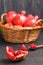 Ripe red pomegranates in wicker basket and seeds in spoon closeup photography on black background.