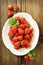 Ripe red strawberries from organic cultivation in a rustic design bowl on a brown wooden board