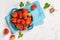 Ripe red strawberries on a plate on stone background, top view