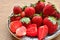 Ripe red strawberries with a round saucer on the brown wooden table