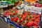 Ripe red strawberries are sold on the counter of an Italian vegetable store in plastic containers.