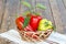 Ripe red and yellow bell peppers in a wicker basket on towel wit