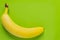 Ripe single banana on bright green background. Minimal flatlay, top view, copy space