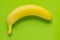 Ripe single banana on bright green background. Minimal flatlay, top view, copy space