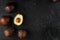 Ripe sliced Hass Avocado with a bone on a black textured background.