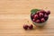 Ripe stella cherries in porcelain bowl on wooden board with copy space