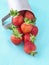 Ripe strawberries from aluminium cups on blue background