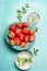 Ripe Strawberries on blue plate with mint and sugar strainer on light blue background, top view.