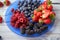 Ripe strawberries, blueberries, blueberries, raspberries on a blue plate on a white textural wooden background. Healthy eating