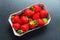 Ripe strawberries in a carton on a dark background