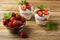 Ripe strawberries and layered cream cheese dessert on wooden background