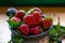 Ripe strawberries lie in a brown mug along with mint leaves on a wooden table among mint leaves