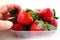 Ripe strawberries in a plastic package on a white background. Delicious fresh berries in a container for sale to