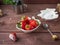 Ripe strawberries in a white plate on a wooden tray. Sugar powder in a small plate.