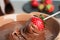 Ripe strawberry dipping into chocolate fondue