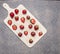 Ripe strawberry from home garden, on white cutting board on a granite table top view