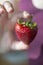 Ripe strawberry in shape of heart holding by young woman