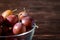 Ripe sweet plum fruits in glass bowl on dark moody wood table background, hard light, copy space