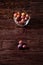 Ripe sweet plum fruits in glass bowl near with scattered plums on dark moody wood table background, hard light, copy space