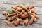 Ripe tamarind fruit, leaves and some tamarind seeds on wooden table