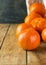 Ripe tangerines vibrant color scattered on plank wood table. White wicker basket. Rustic interior. Harvest holiday concept.