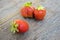 Ripe three red sweet strawberries on wooden table,