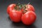 Ripe washed tomatoes on vine on slate background