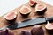 Ripe whole and cut delicious figs on wooden chopping board with knife isolated on white.