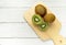 Ripe whole kiwi fruit and half kiwi fruit on wooden cutting board. Full depth of field. vegan food concept