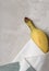 Ripe yellow banana wrapped in kitchen towel on gray mottled tile with copy space