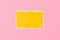 Ripped yellow paper torn edge sheet on a pink background. Template with piece of color paper