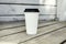 Ripple white paper cup of coffee to takeaway at the wooden floor terrace outside.