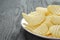 Rippled potato chips in white plate on wood table