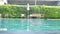 Rippled water in swimming pool with comfortable deck chairs and green plant background